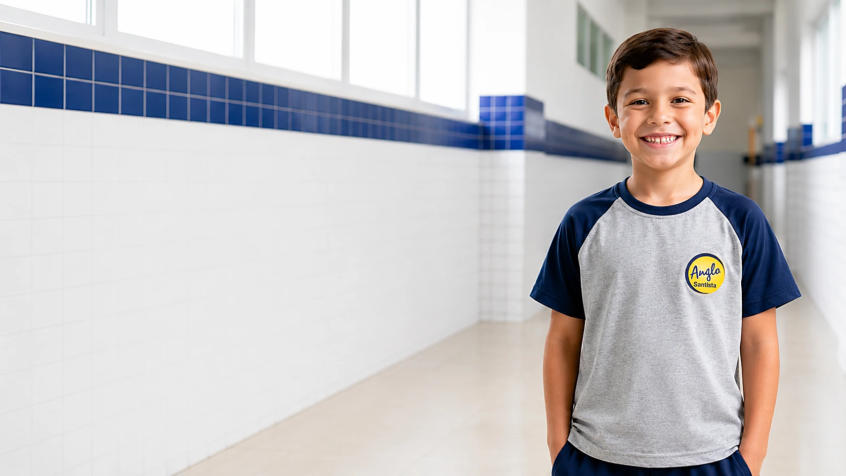 Aluno do Colégio Anglo Santista sorrindo no corredor da escola, com o uniforme